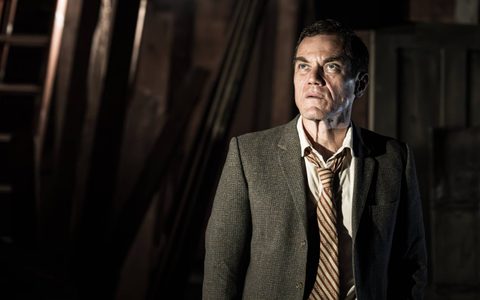 Michael Shannon wears a grey suit and striped tie. He looks up and to the side towards something off camera.