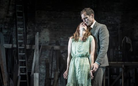 Ruth Wilson wears a green dress and stands in front of Michael Shannon, who wears a grey suit. She leans her head back on his shoulder and he rests his head on hers.