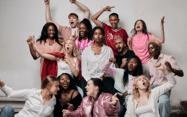 The Almeida Young Company smiling against a white wall dressed in pink and white