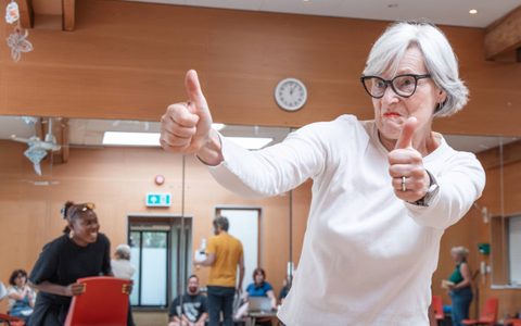 A person has two thumbs up in a rehearsal room.