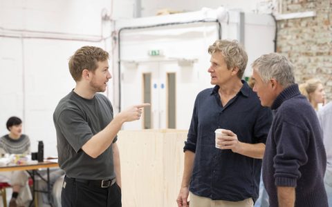 Jack Holden, Charles Edwards, and Robert Portal stand in a rehearsal room, in conversation.