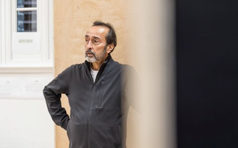 Bijan Daneshmand stands in the Under the Shadow rehearsal room with one hand on his hip.