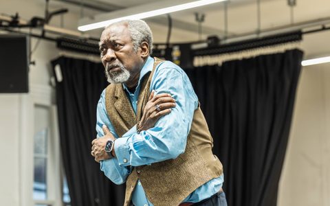 Joseph Mydell stands with arms wrapped around himself. He wears a blue shirt and brown waistcoat. He has a frightened expression.
