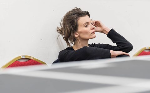 Emily Barber wears a black jumper and sits in a rehearsal room.