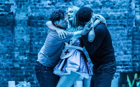 Romola Garai, Tom Mothersdale and Olivier Huband stand in an embrace.