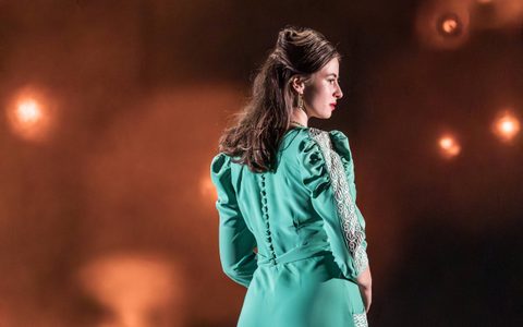 Agnes O’Casey wears a teal dress and looks off to the side with her back to the camera.