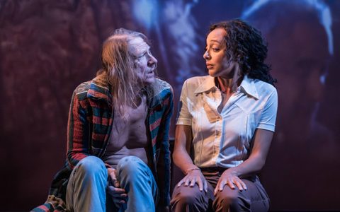 Jerry Killick wears a blue and red open jacket. He sits beside Adelle Leonce, who wears a white shirt and dark trousers. They look at each other as Jerry speaks.