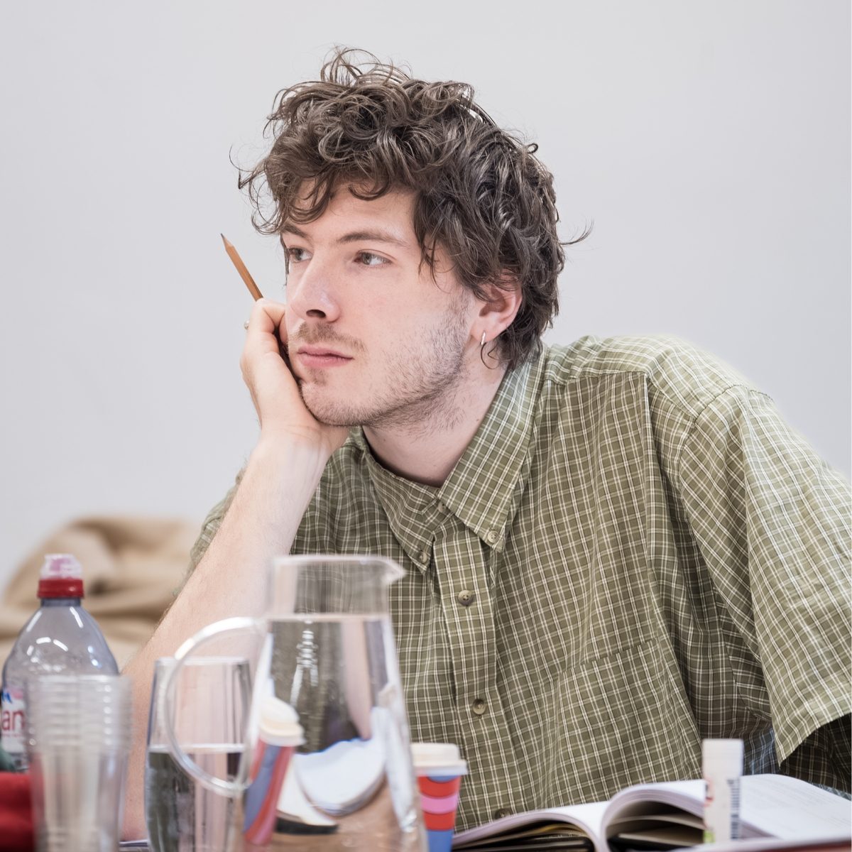 Photo of Sam Grabiner, holding a pencil, in the Almeida rehearsal room