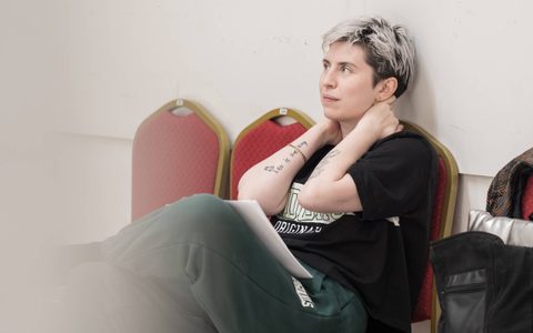 A Doll’s House adaptor Anya Reiss sits on a red chair with both arms on her neck.