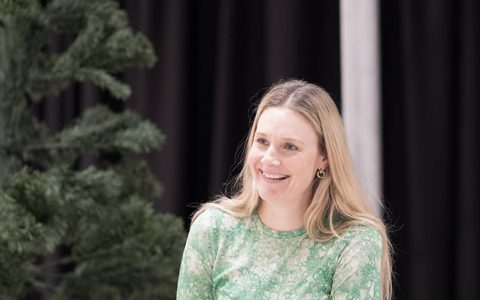 Romola Garai smiles with one hand in her pocket.