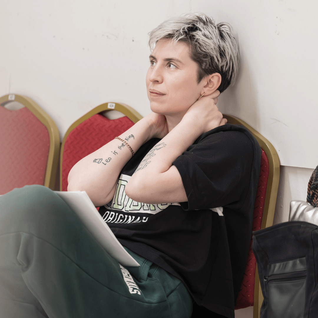 A Doll’s House adaptor Anya Reiss sits on a red chair with both arms on her neck.