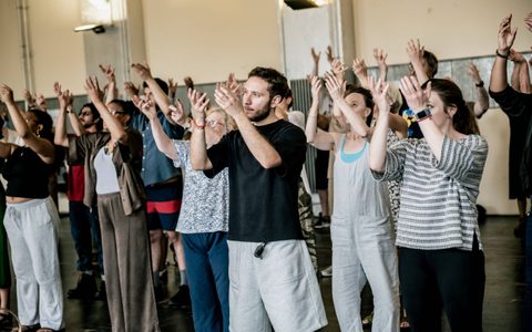 A large group of people stand together with their arms raised.
