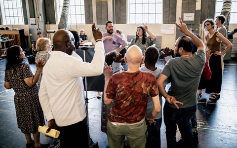 A large group of people stand in a circle with peace fingers.