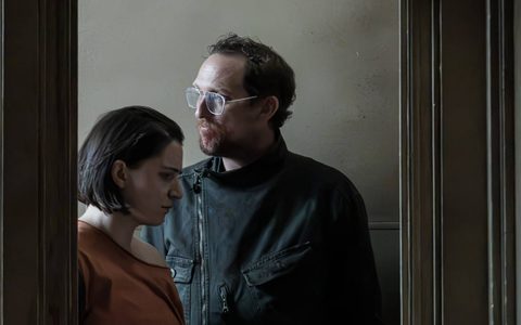 Leo Bill and Pearl Chanda stand in a doorway, veiled in shadow.