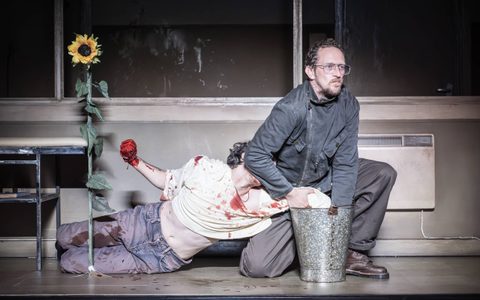 Leo Bill puts Luke Cinque-White's hand in a grey bucket. Luke's other hand is covered in blood.